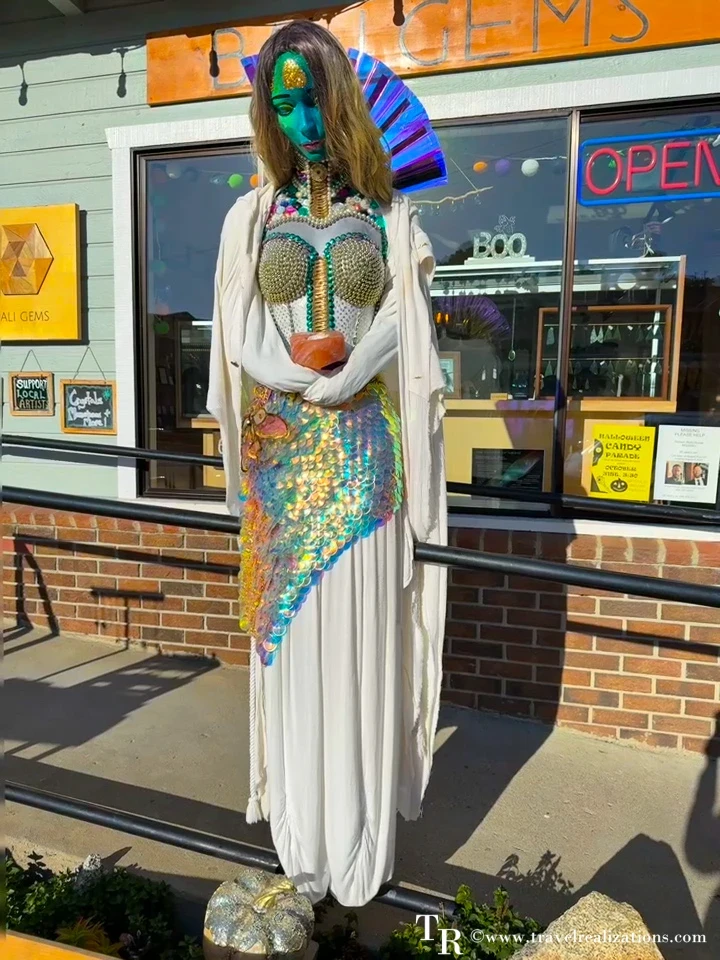 Mermaid scarecrow with a sequined tail and shell top outside a shop in Cambria