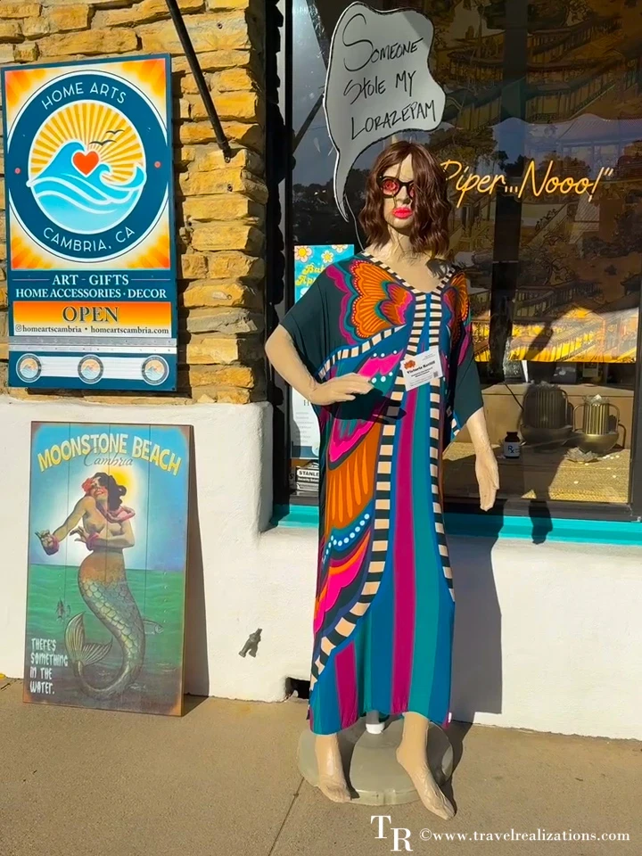 Scarecrow in a colorful patterned dress outside an art and gift shop in Cambria