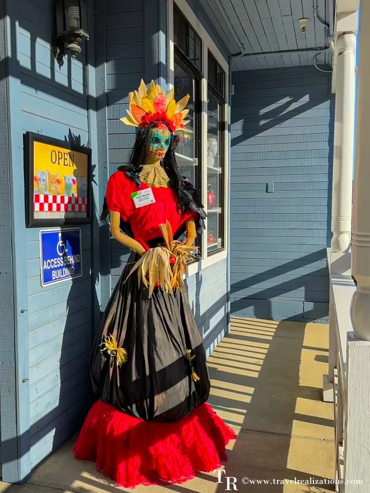 Day of the Dead style scarecrow in a red and black dress with a floral headdress in Cambria