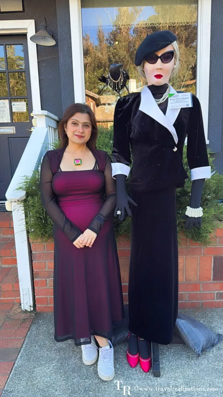 Chirasree of Travel Realizations beside an elegant scarecrow in black velvet, beret and sunglasses in Cambria