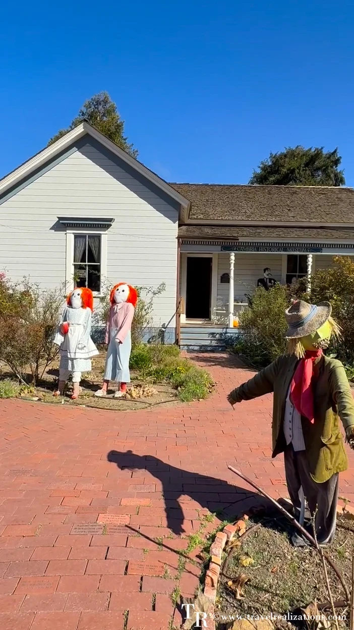 Scarecrows on the brick path and lawn of a historic white house in Cambria's East Village