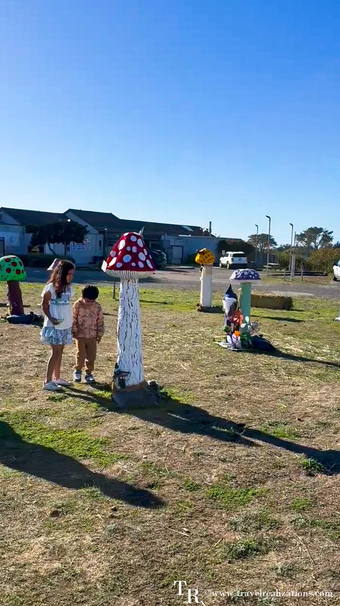 Kids walking among giant mushroom scarecrows at the San Simeon scarecrow display